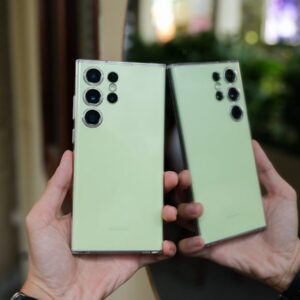 a pair of hands holding two green cell phones